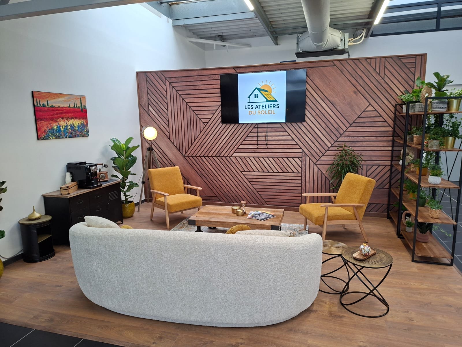 Le salon du showroom : canapé, fauteuils jaunes et mur en bois à chevrons.